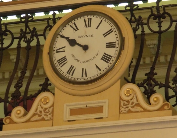 a clock on top of a balcony in front of iron railings