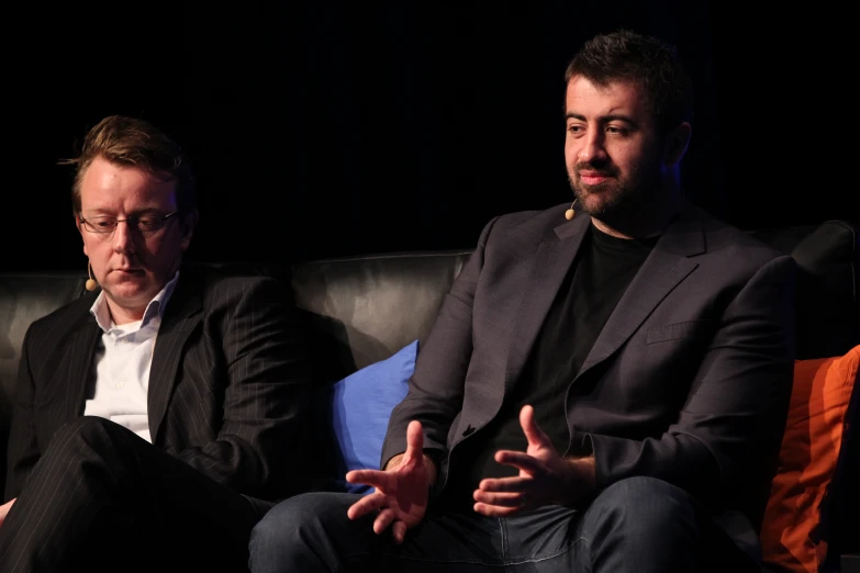 two men sitting on a couch facing each other