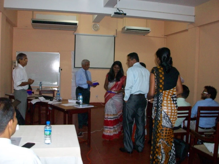 a man presenting at a meeting with people sitting at desks