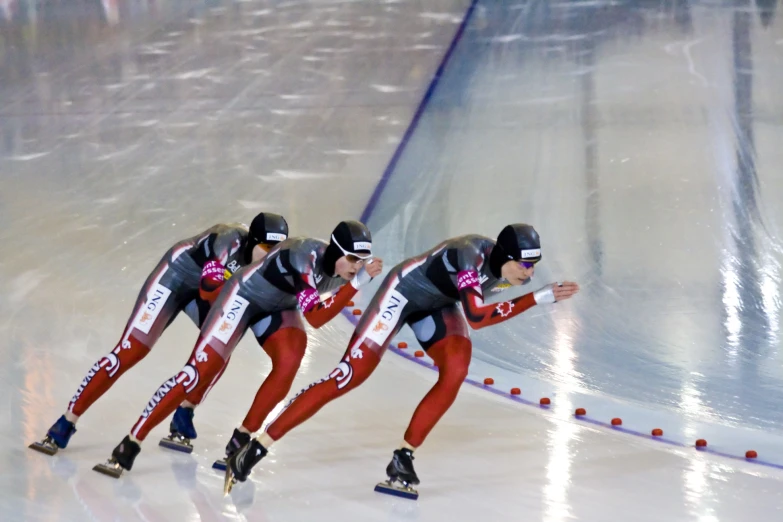 some ice skating competitors with helmets on during a race