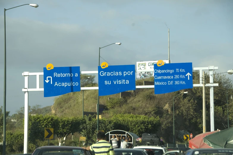 many blue signs pointing to different destinations in a city