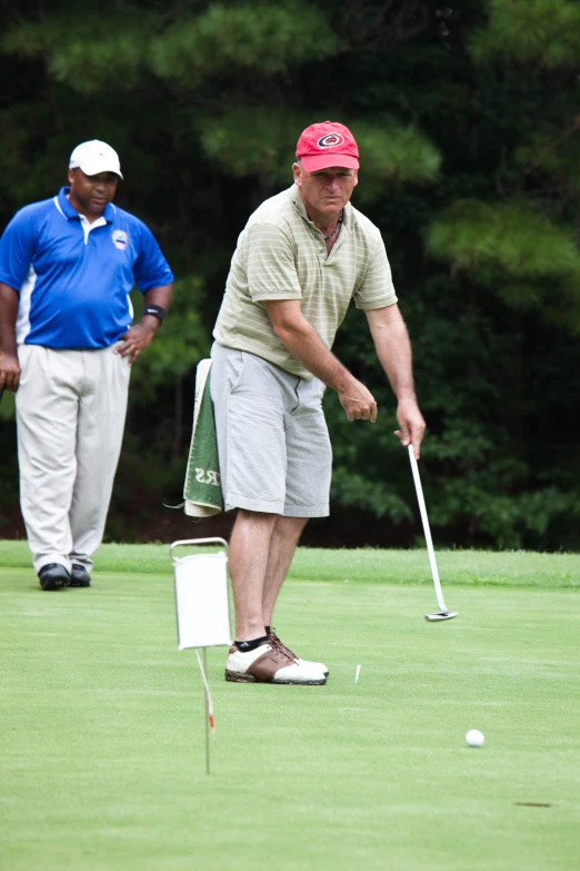 two older men are on the green playing golf