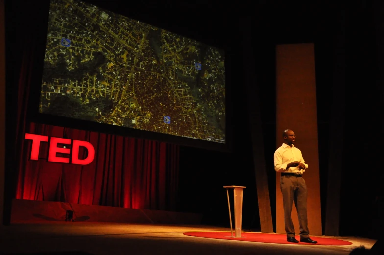 a man standing at a podium in front of a screen