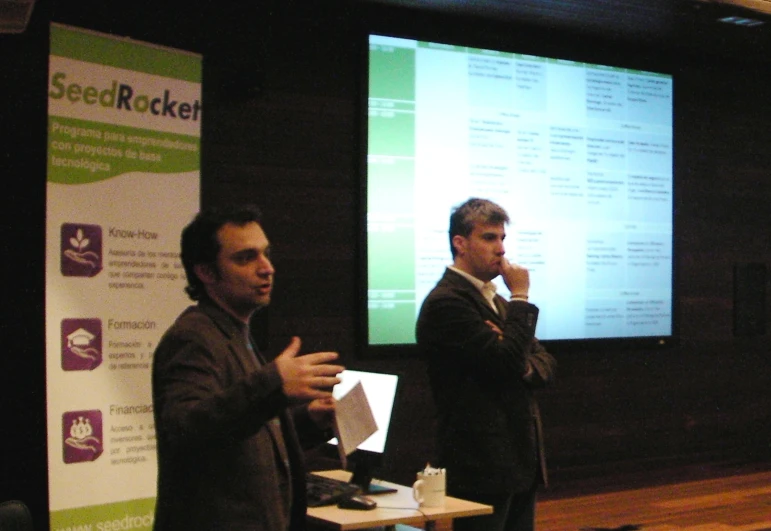 two men are standing in front of a projection screen