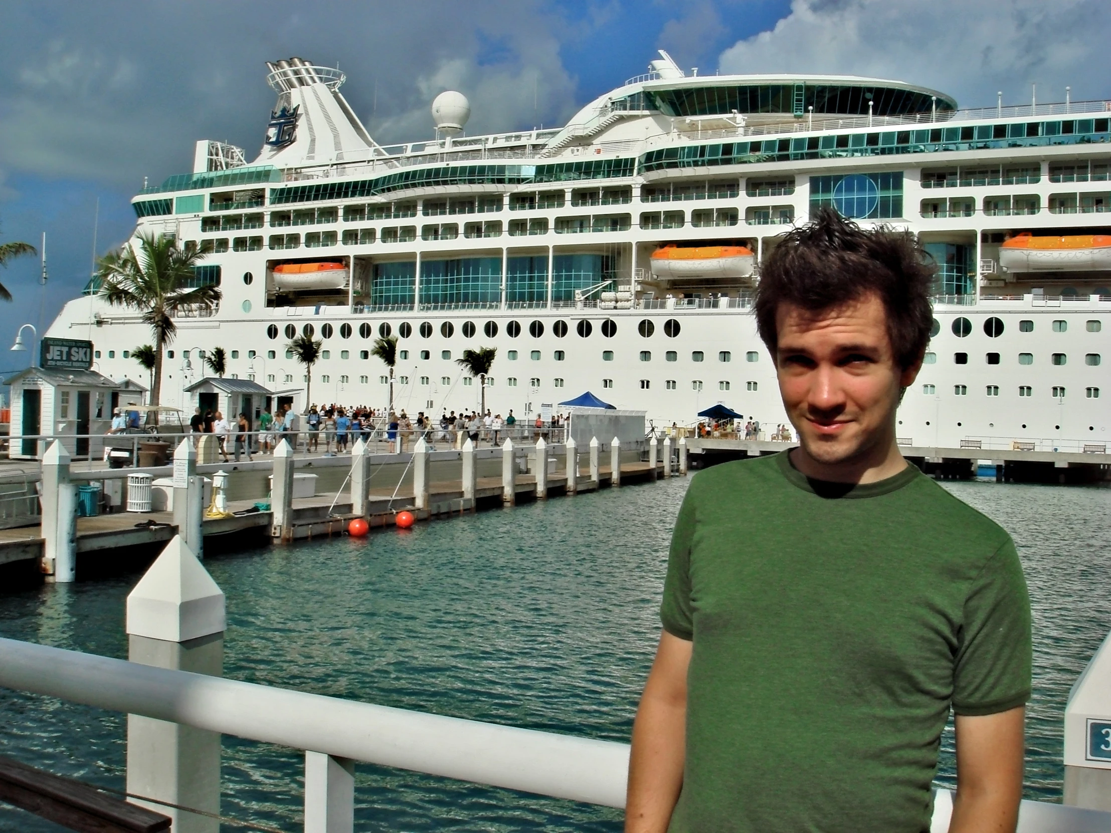 a man posing in front of a large cruise ship