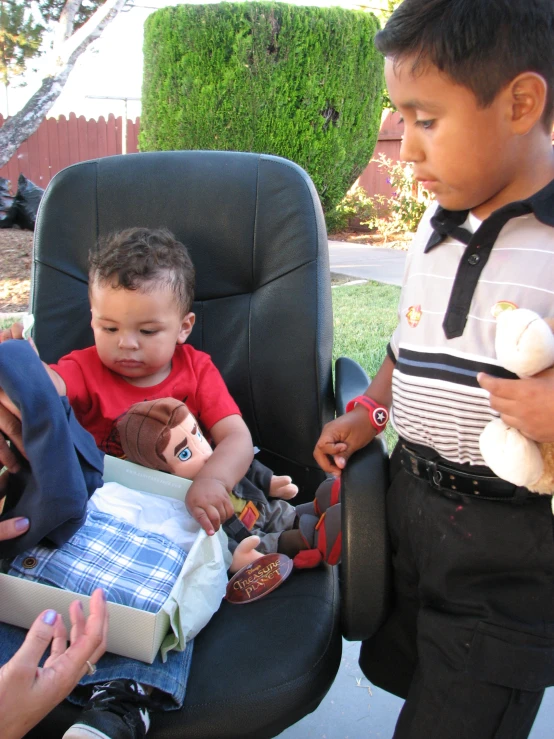 two young children in black chairs playing with a boy