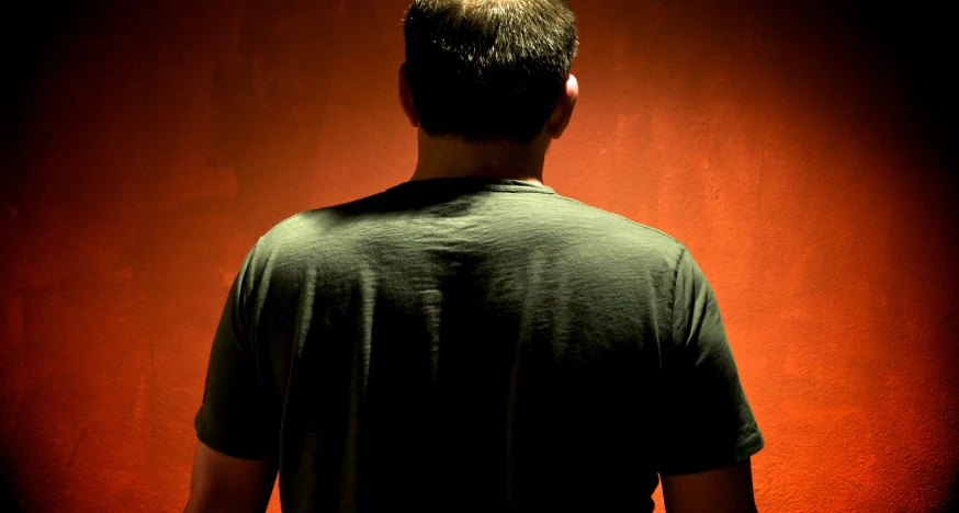 the back view of a person in front of an orange wall