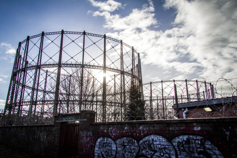 a metal roller coaster with the sun behind it