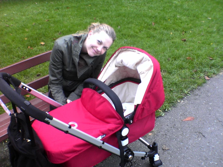 a lady posing for a po while sitting on a bench next to a stroller