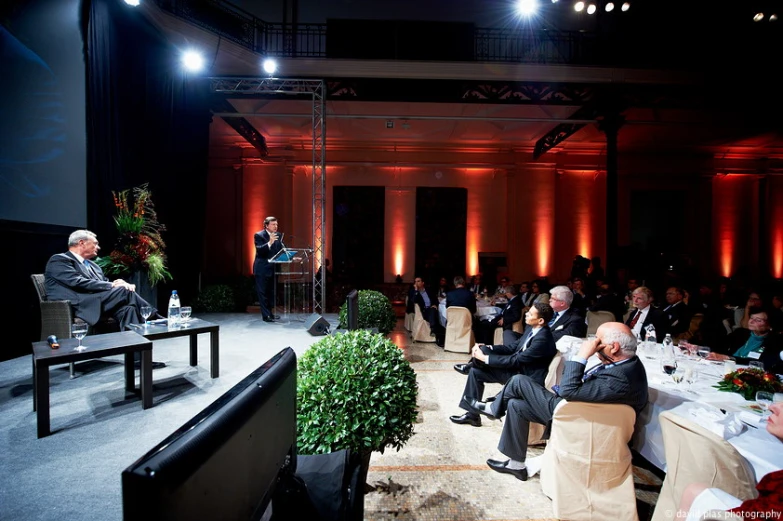 people sitting at a table with one man standing and talking to others