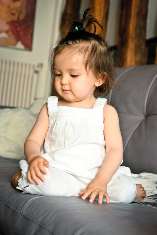 a little girl sitting on the couch and looking down