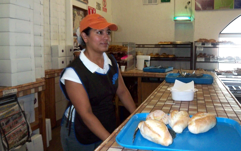 woman at bakery counter wearing orange hat