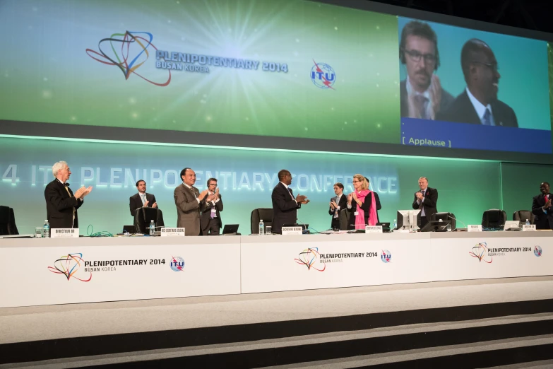 several people sitting at a table in front of a crowd