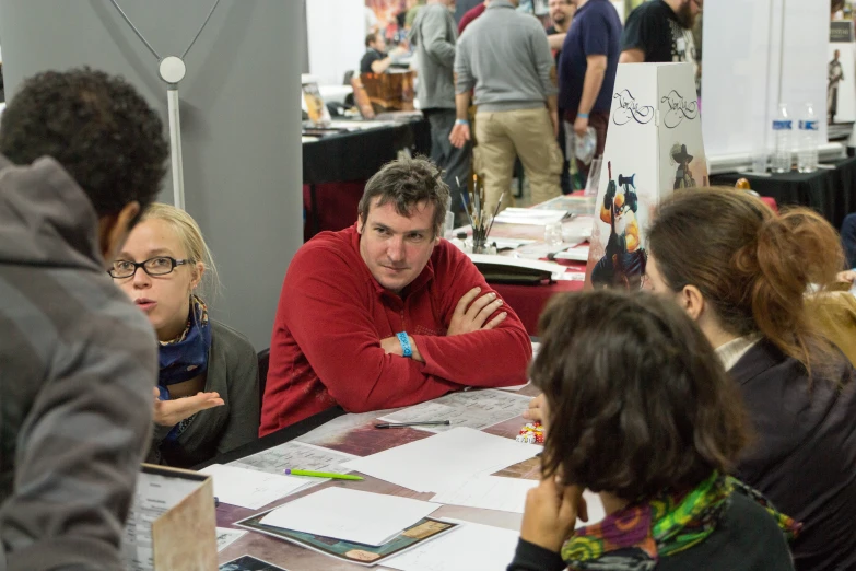 a group of people at a table with papers and pens