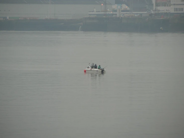 a boat in the middle of a foggy sea with two people on it