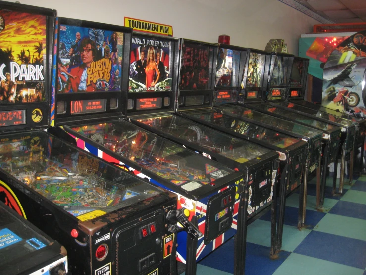 several pinball machines are lined up on a checkerboard floor