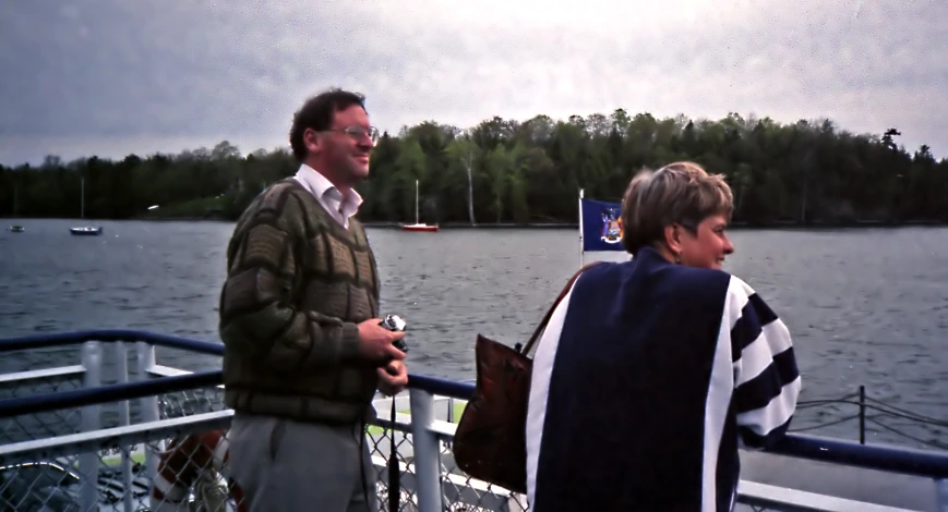 two men stand on a boat in a large body of water