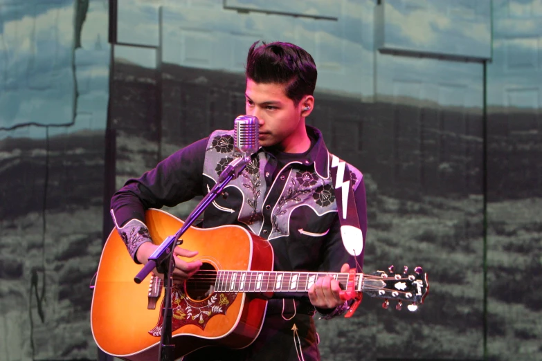 a male singer with a red guitar and microphone