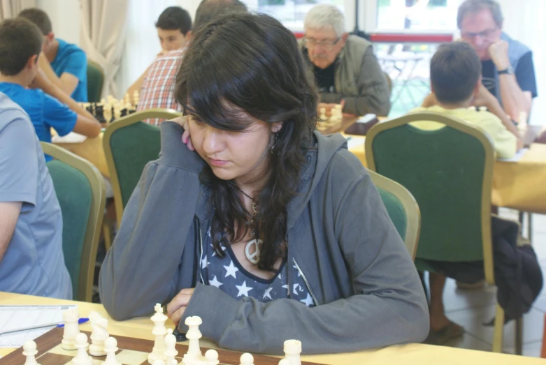 a girl sitting at a table playing chess