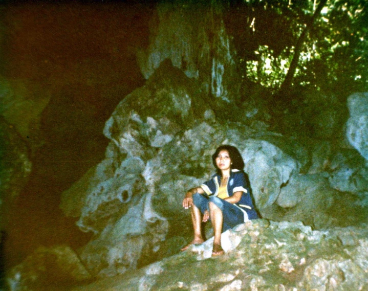 a girl sits on a rock in a forest