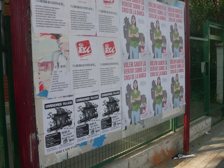 several posters on a wall near a fence