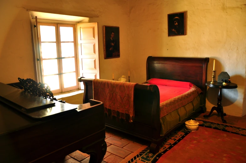 a bedroom with a bed in the corner and a wooden desk nearby