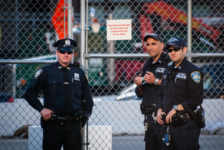 two police officers in front of a fence looking at soing