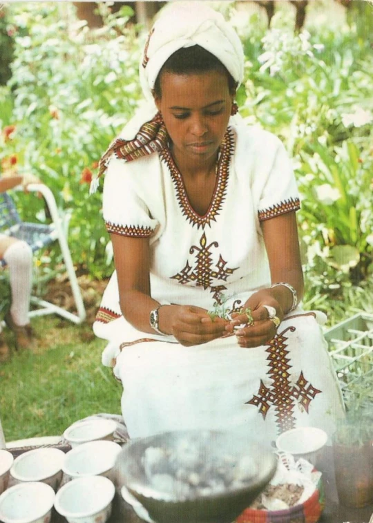 a woman in white dress preparing food at outdoor table