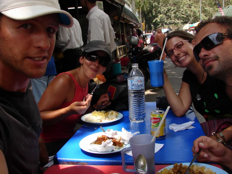 four people sitting at a table outside eating food