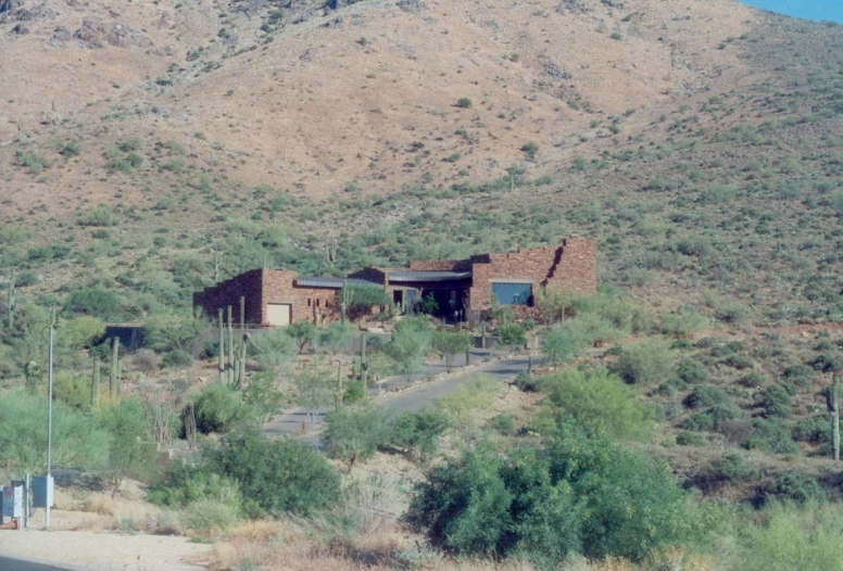 a big desert like mountain side with a home built in the middle