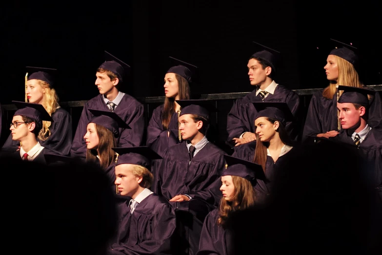 graduation students in caps and gowns wait for their turn to sing