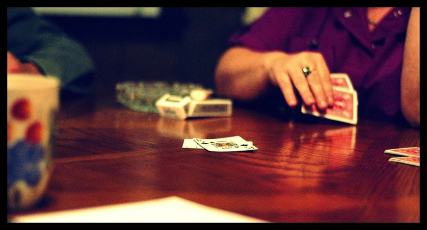 a woman sits at a table while playing cards