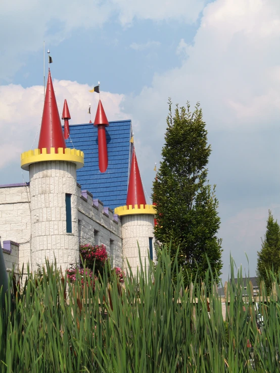 a white castle with blue and yellow roof surrounded by green trees