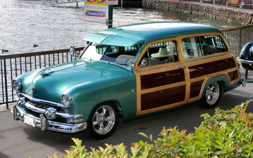 vintage station wagon is parked on the curb next to the water