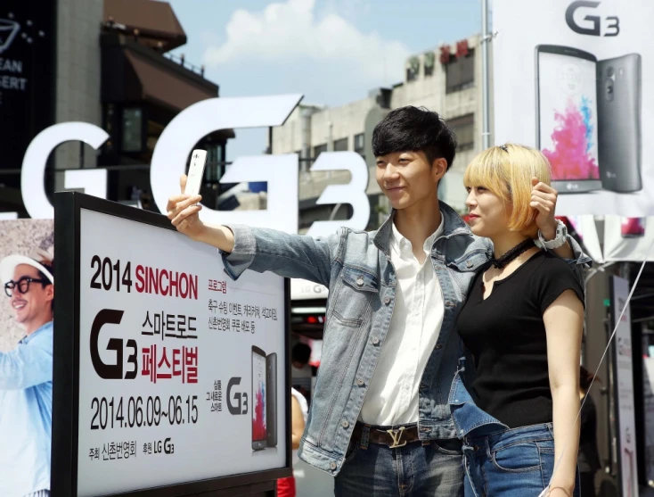 a man and woman standing behind a banner with cell phones