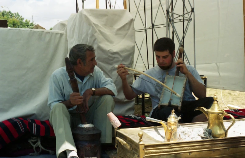 two men sitting next to each other on the ground