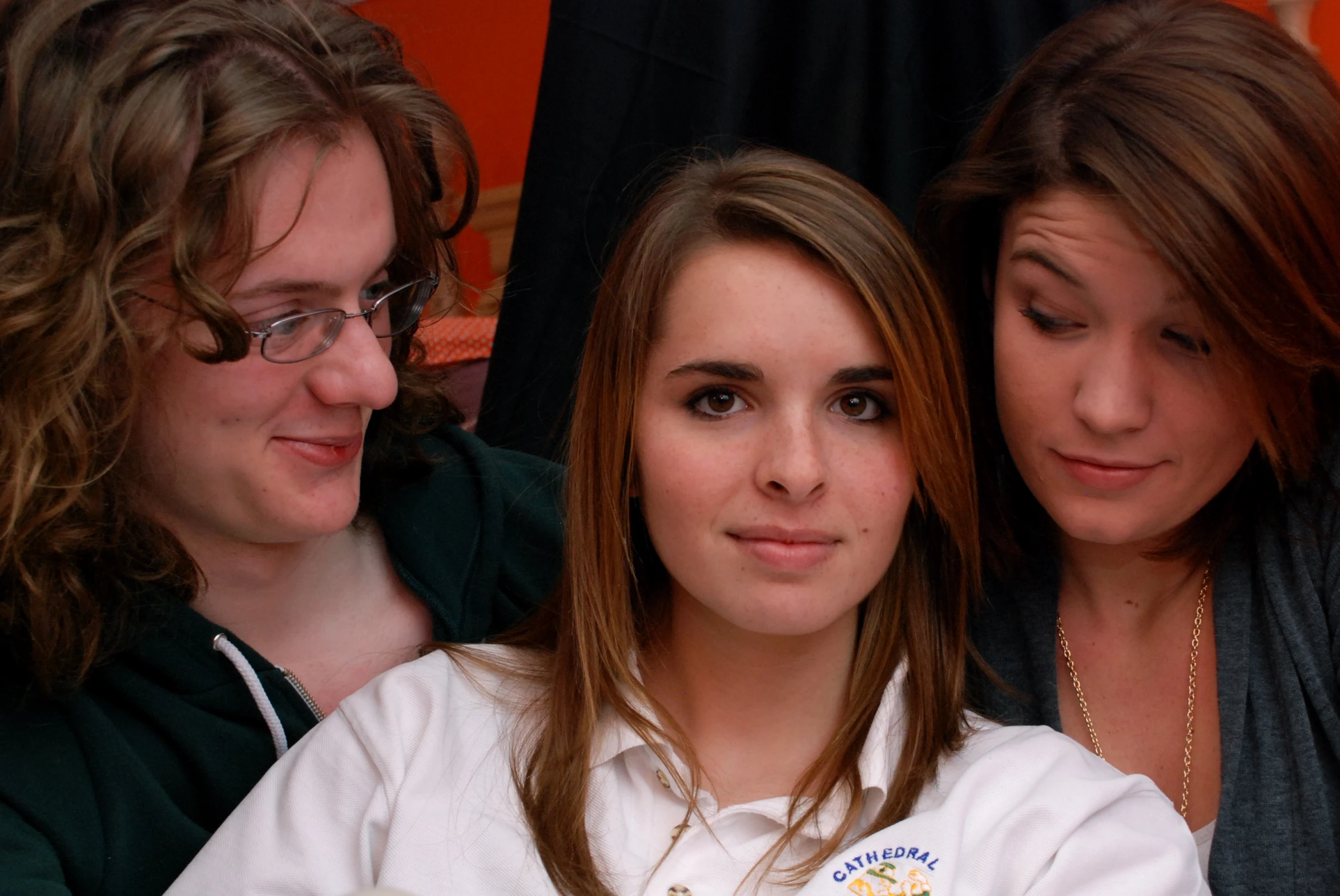 three women posing for the camera holding onto one another