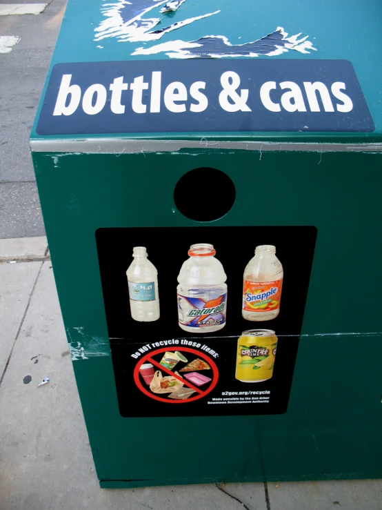 a large bottle and cans machine sitting on the street