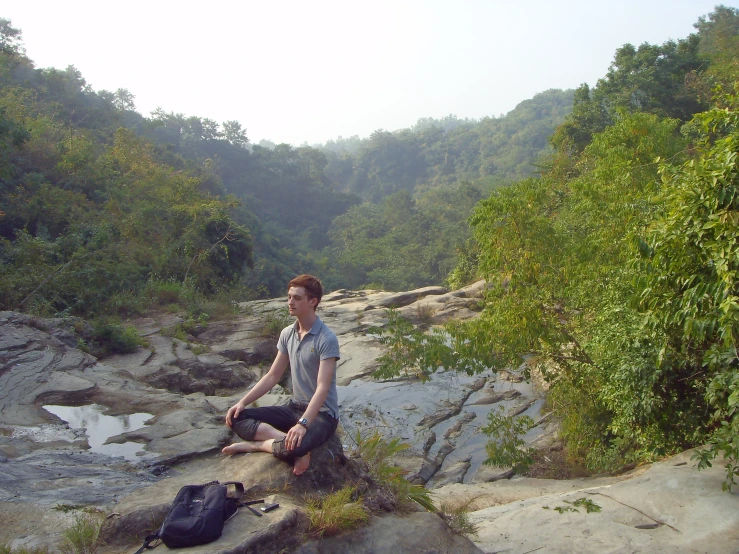 a man sitting on a rock in front of the ocean