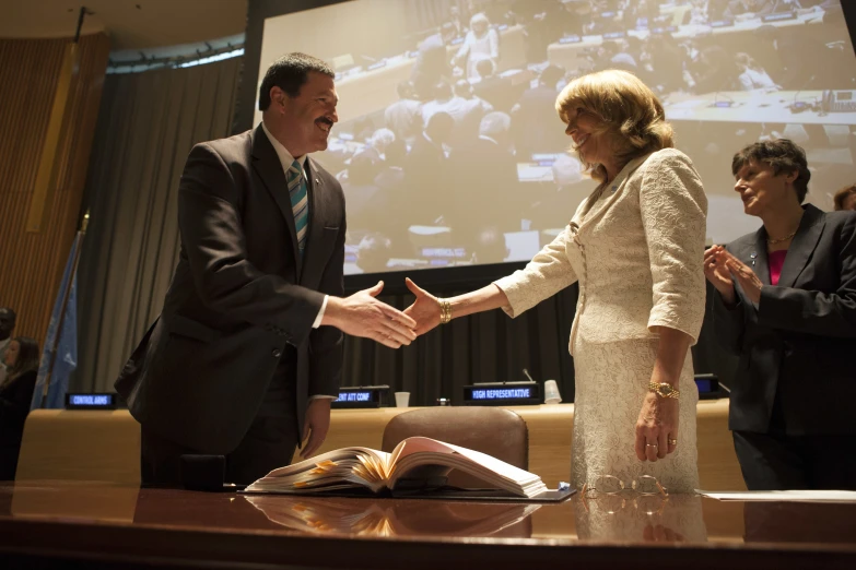 two people shake hands in front of a class of people