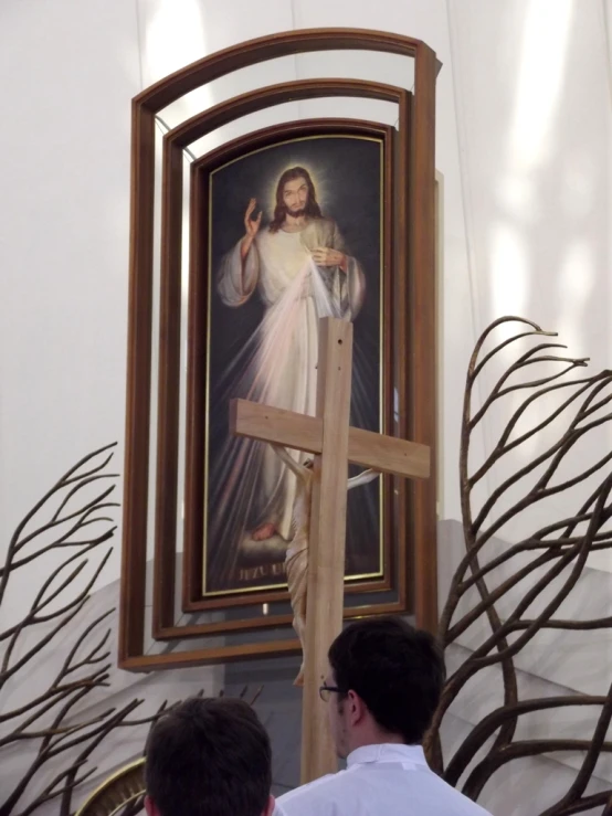 a man holding up a wooden cross while it hangs on a wall