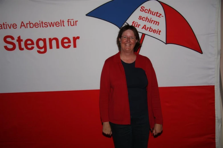 a woman wearing black shirt and jeans stands in front of the german language logo