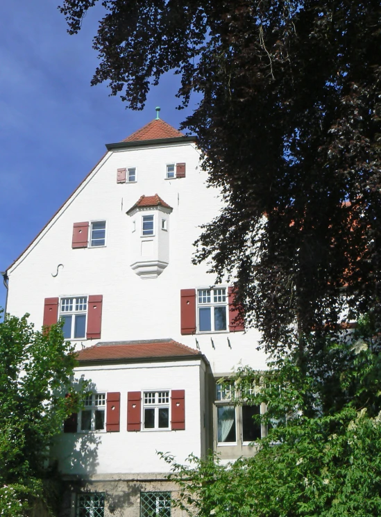 a tall white building with red shutters and white walls