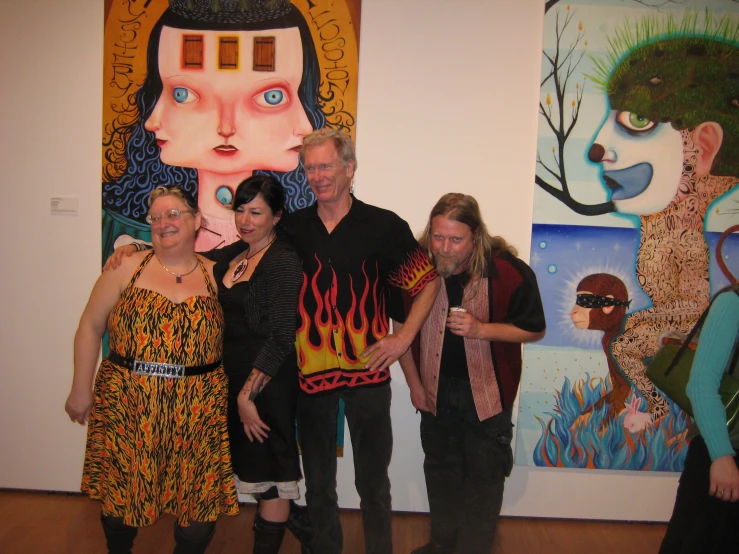 people posing in front of several colorful wall hanging