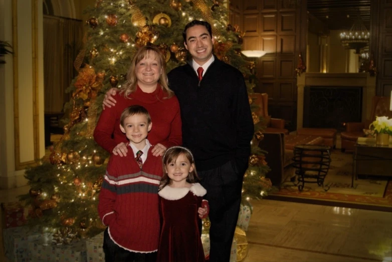 this is a family posing for a picture near a christmas tree