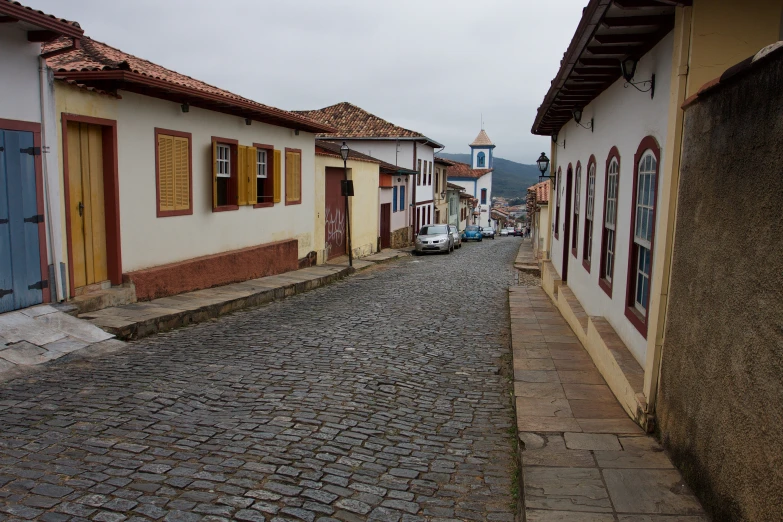 a street lined with old looking buildings on top of a cobblestone road