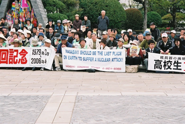 a group of people holding signs sitting on top of a brick sidewalk
