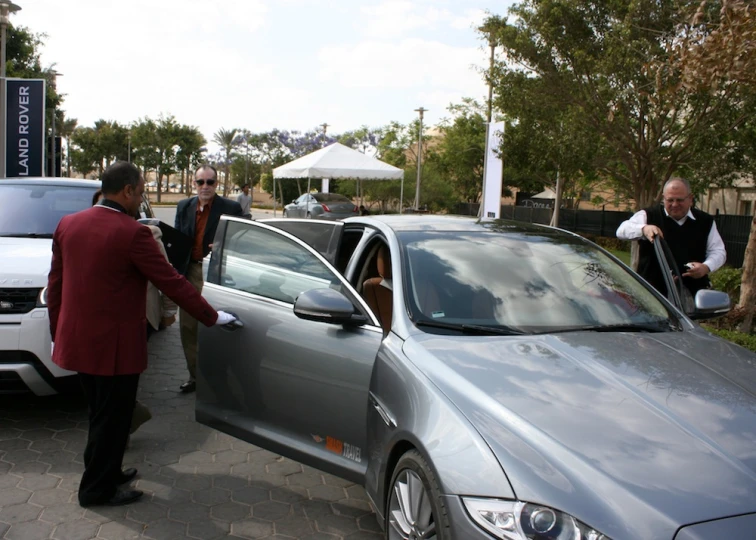 men in business suits talk to people about their cars