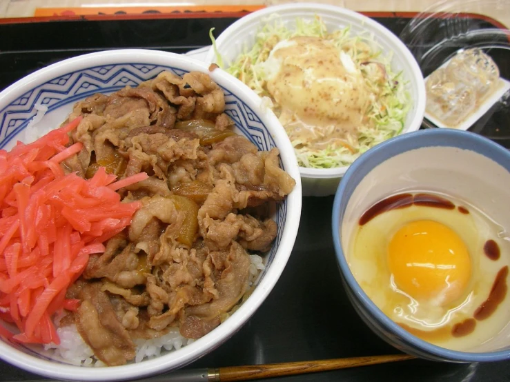 a tray with bowls of asian food, eggs and vegetables