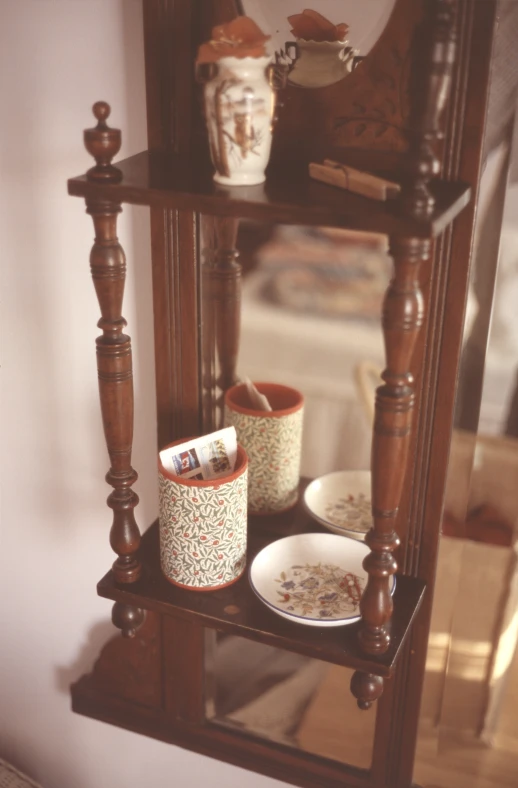 a small shelf with two plates, a mirror and dishes